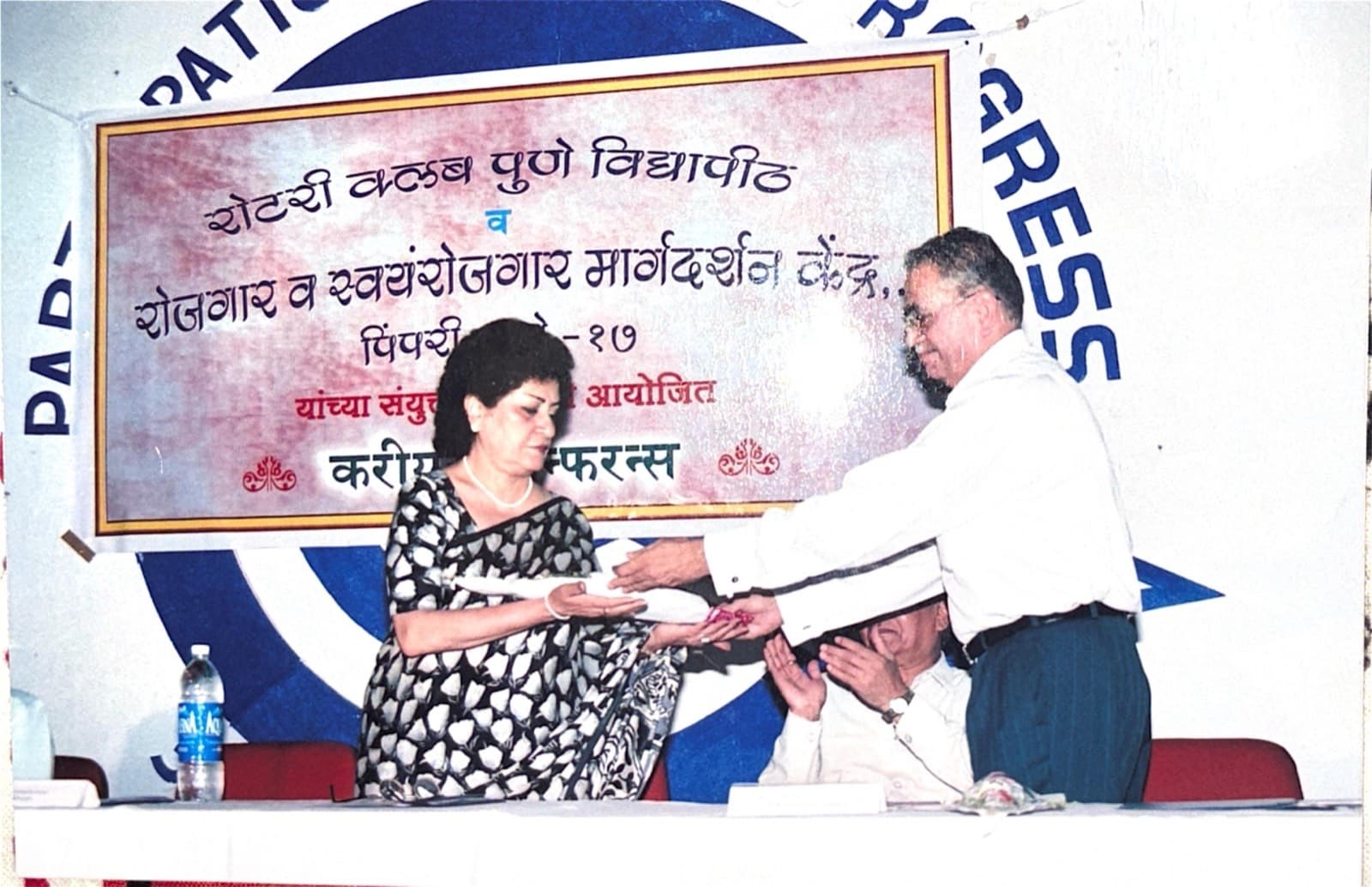 A Rotarian felicitating a guest on stage at a careers conference, beneath a Marathi banner naming the club.
